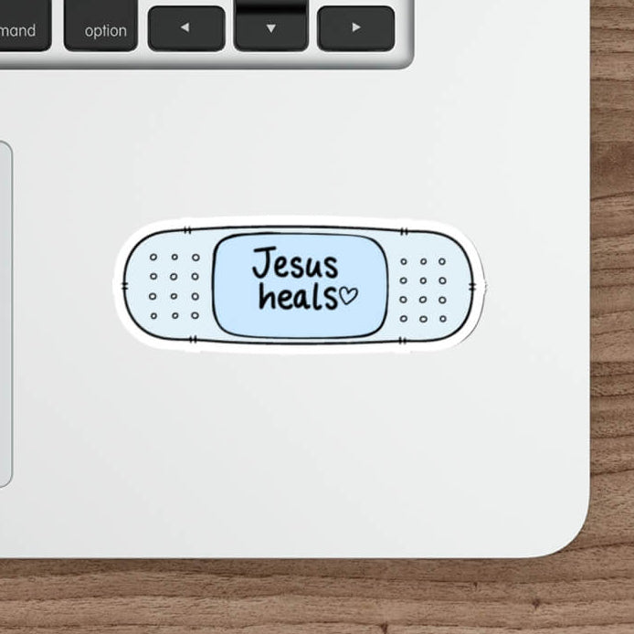 Cute blue Christian bandage sticker featuring the words Jesus Heals with a small heart in a simple kawaii design.
