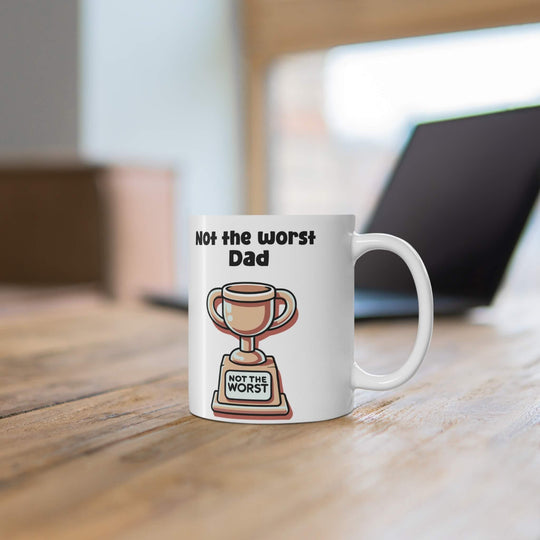 White ceramic mug with 'Not the Worst Dad' and a trophy design, ideal for gifting, 11 oz capacity, microwave and dishwasher safe.