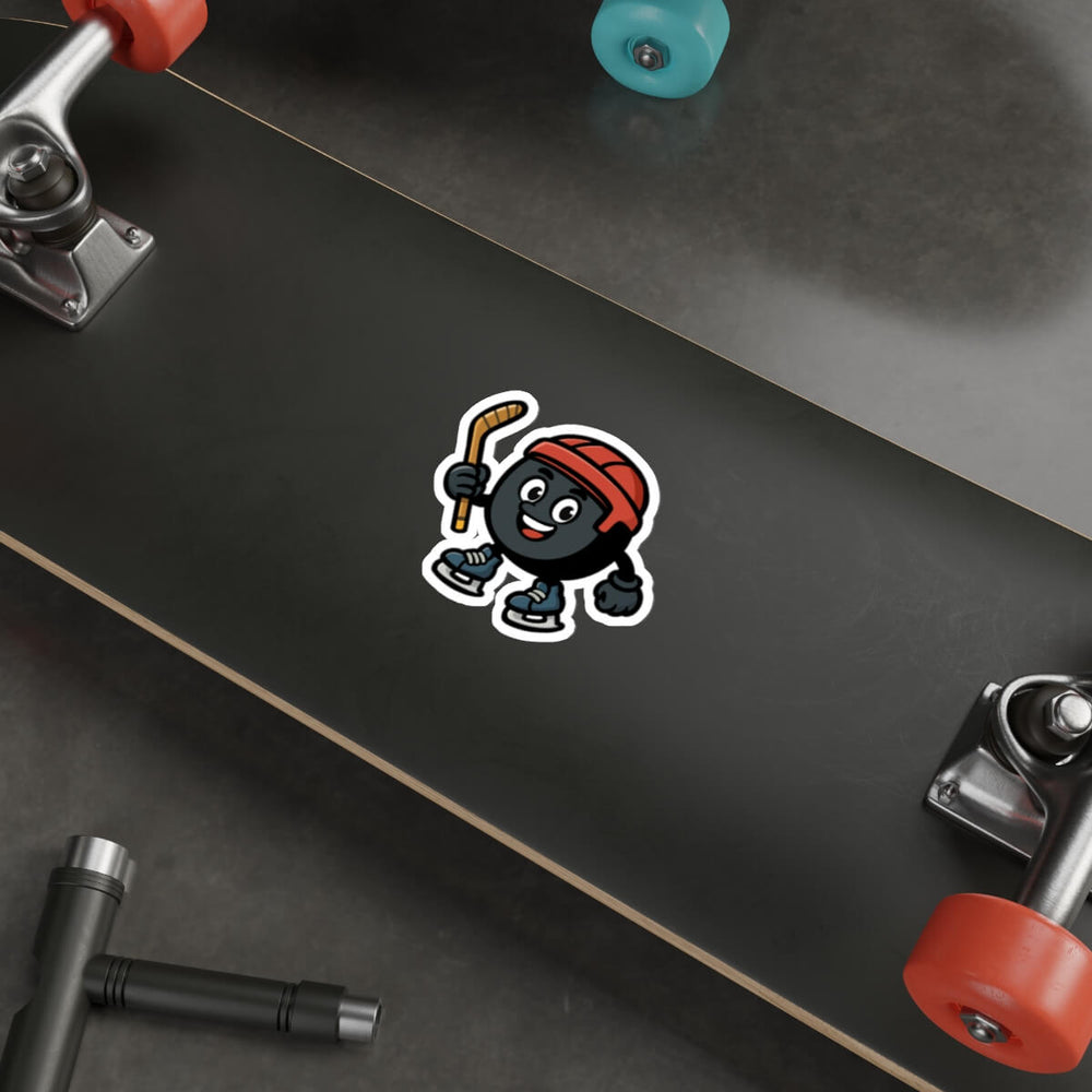Vinyl sticker of a cartoon hockey puck character with a red helmet and skates, shown on a silver laptop near a keyboard.