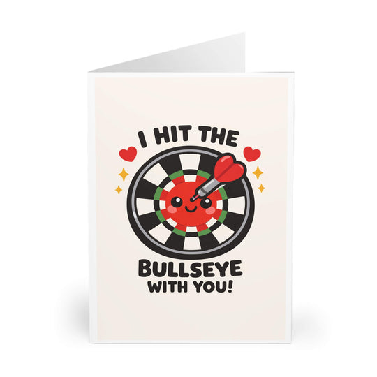 Cute cartoon dartboard with heart-tipped dart and smiling face, featuring the phrase “I hit the bullseye with you,” playful love-themed greeting card design