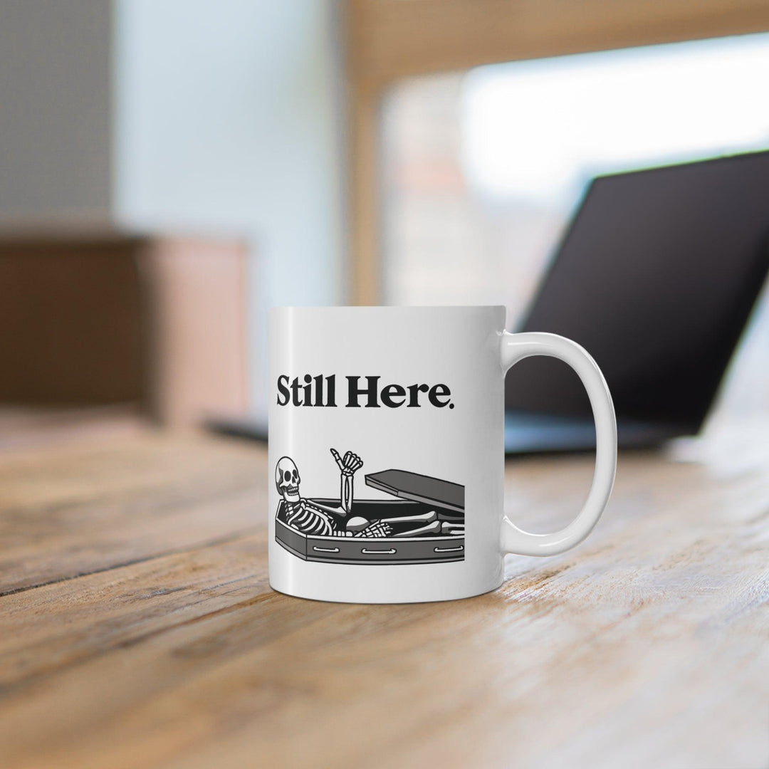 Minimalistic white ceramic mug with the text 'Still Here' and a simple design, perfect for a subtle yet thoughtful coffee companion