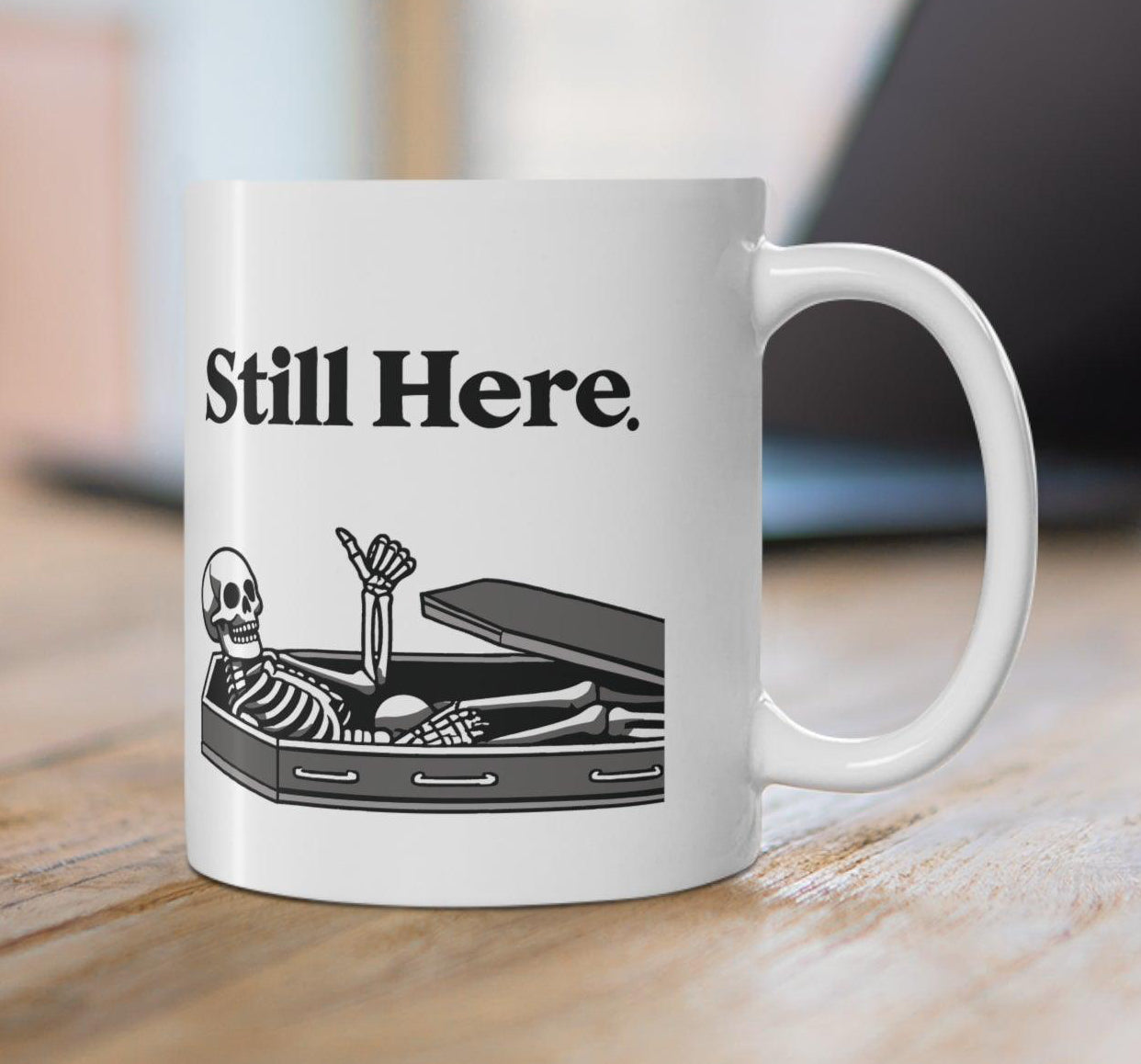 Minimalistic white ceramic mug with the text 'Still Here' and a simple design, perfect for a subtle yet thoughtful coffee companion