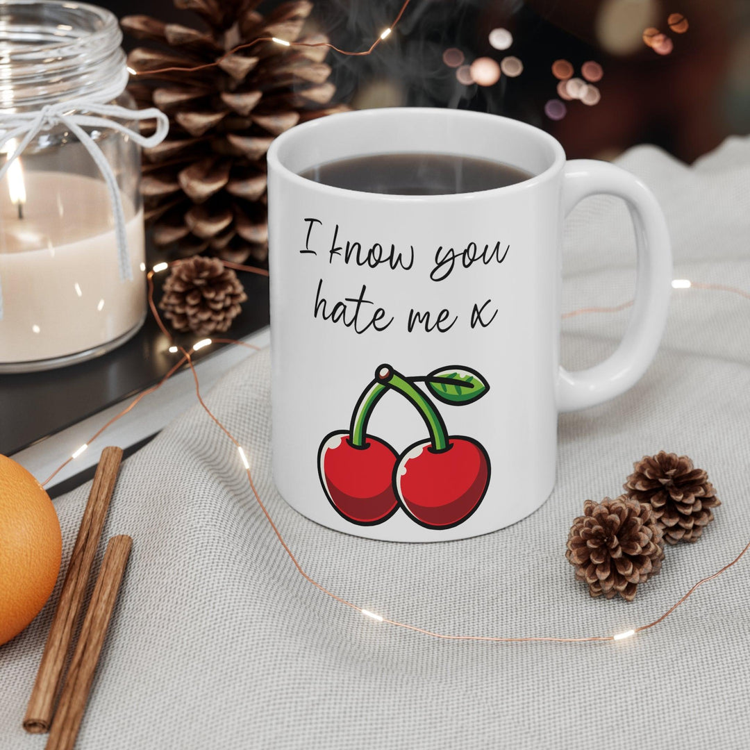 White ceramic mug featuring a pair of cherries with the playful text 'I Know You Hate Me,' perfect for adding a bit of cheeky humor to your coffee routine.