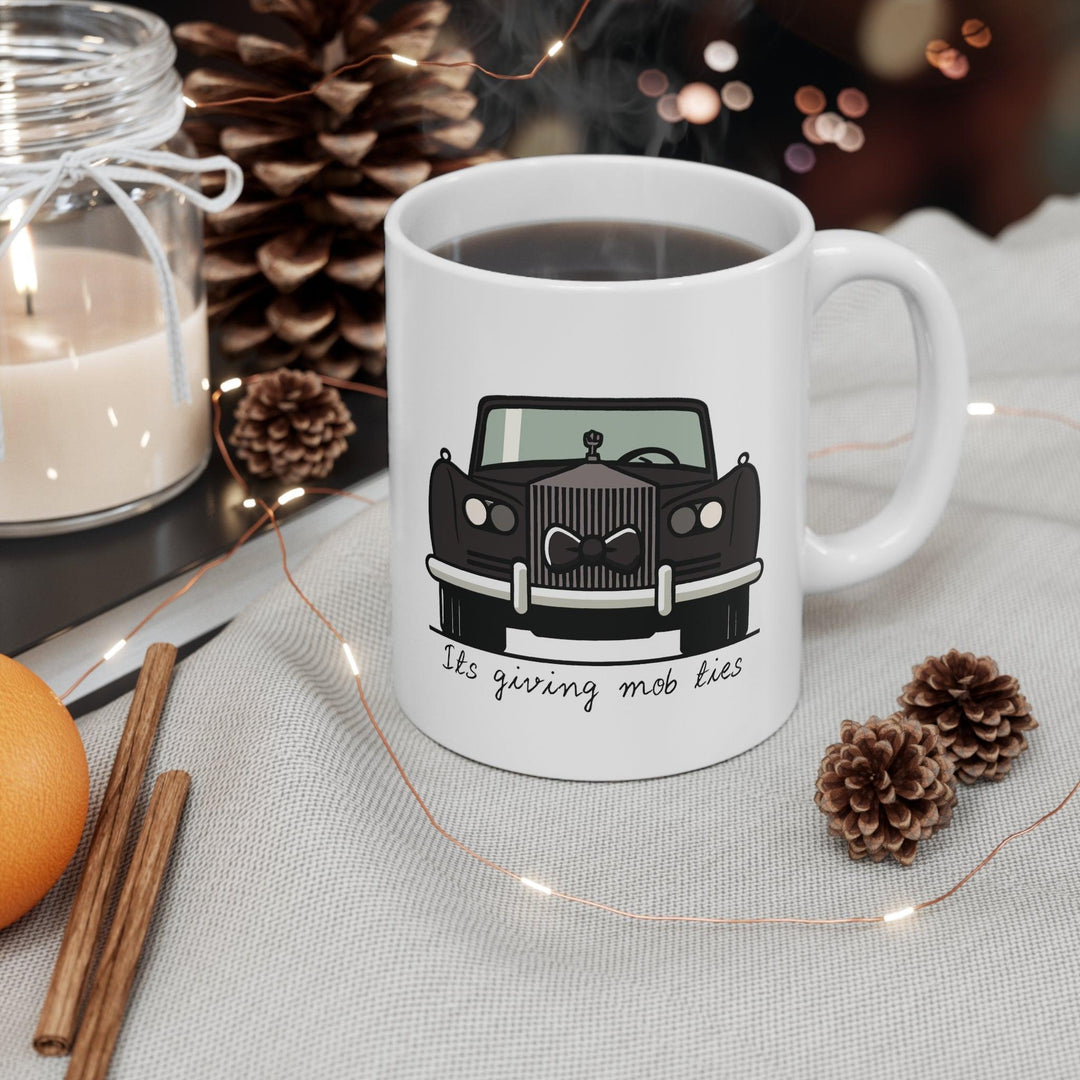 White ceramic mug featuring a black car design with the phrase 'It's Giving Mob Ties,' perfect for anyone with a love for mob-inspired humor.