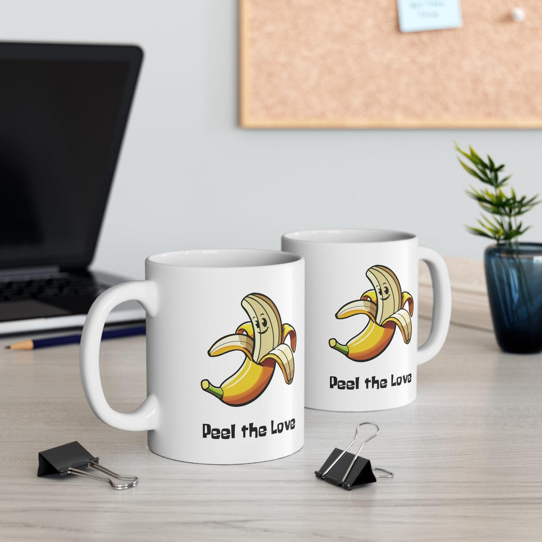Fun white ceramic mug featuring a smiling cartoon banana and the playful text 'Peel the Love,' ideal for spreading positivity with a cute design