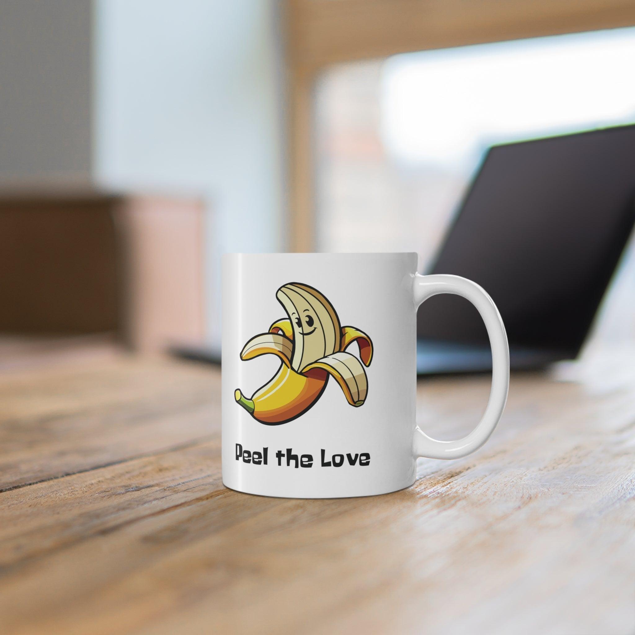 Fun white ceramic mug featuring a smiling cartoon banana and the playful text 'Peel the Love,' ideal for spreading positivity with a cute design