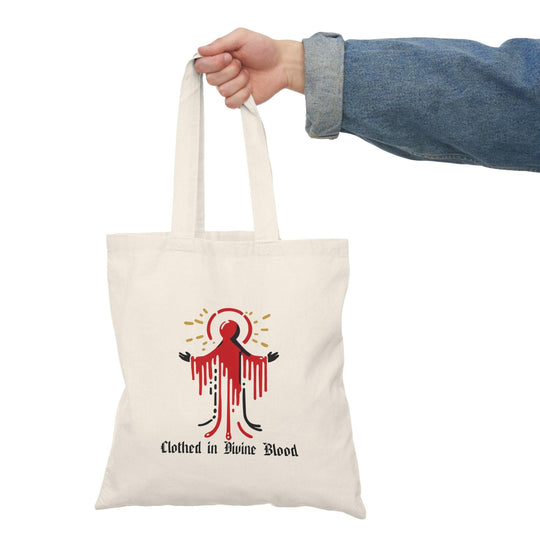 Tote bag featuring a striking design with the phrase 'Clothed in Divine Blood' artistically displayed alongside vivid graphics. The powerful imagery and bold colors convey a message of faith and strength, making it a unique accessory for those who want to express their spirituality with style."

