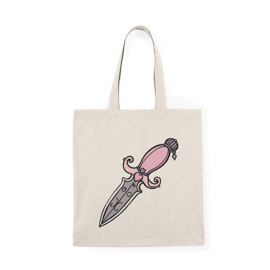 A cream-colored tote bag featuring a bold illustration of a pink dagger with intricate designs on the blade. The eye-catching graphic adds a touch of edgy style, making it a great accessory for those who appreciate unique and artistic designs.