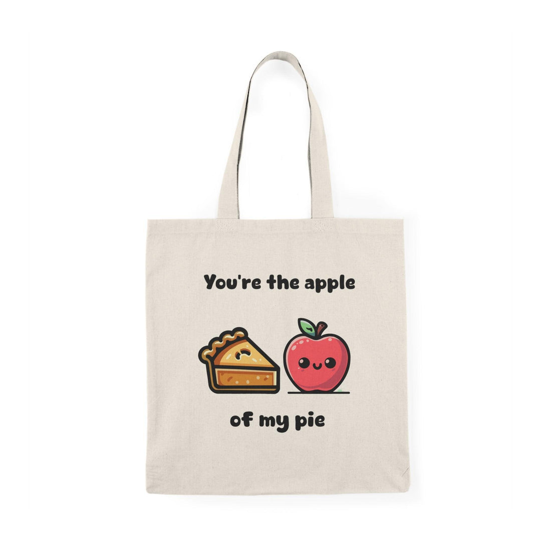 A cream tote bag featuring a delightful graphic of an apple pie with apples on either side and the text 'You're the apple of my pie.' This punny design adds a touch of sweetness and charm, making it an ideal gift for food lovers and those with a sweet tooth.