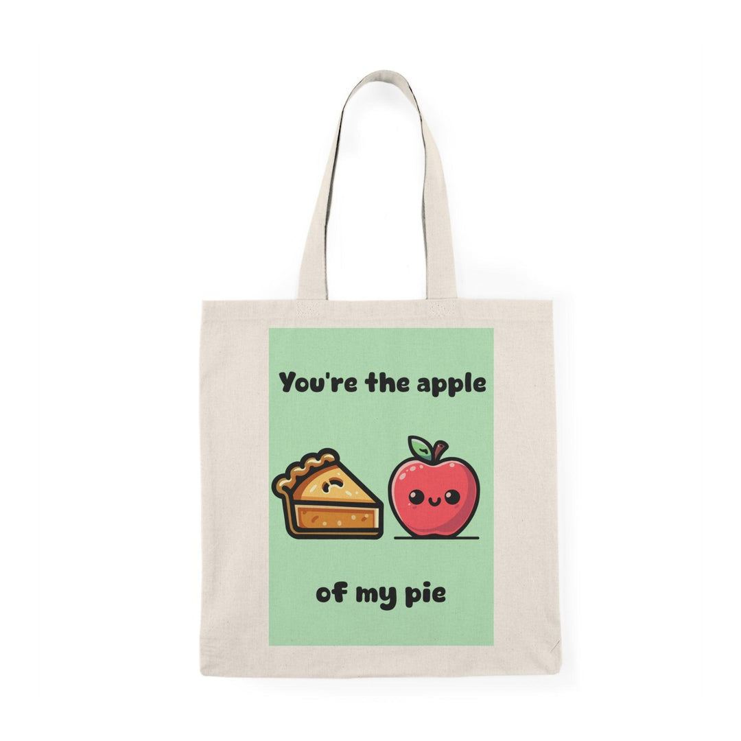 A cream tote bag featuring a delightful graphic of an apple pie with apples on either side and the text 'You're the apple of my pie.' This punny design adds a touch of sweetness and charm, making it an ideal gift for food lovers and those with a sweet tooth.
