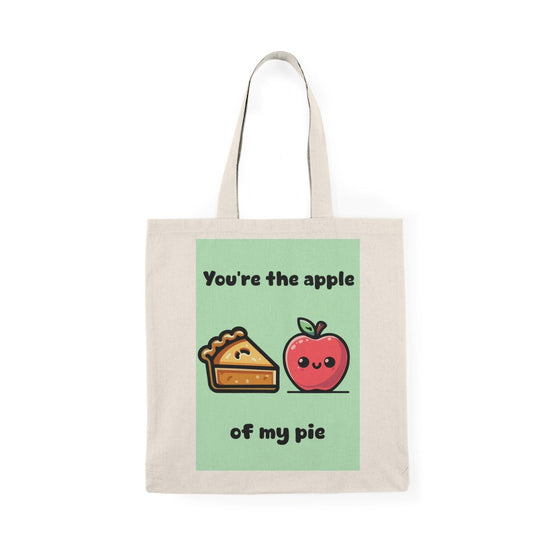 A cream tote bag featuring a delightful graphic of an apple pie with apples on either side and the text 'You're the apple of my pie.' This punny design adds a touch of sweetness and charm, making it an ideal gift for food lovers and those with a sweet tooth.