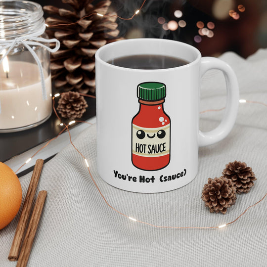 'You're Hot (Sauce)' Mug - "White ceramic mug featuring a hot sauce bottle illustration with the playful text 'You're Hot (Sauce),' perfect for adding spice to your drinkware collection."

