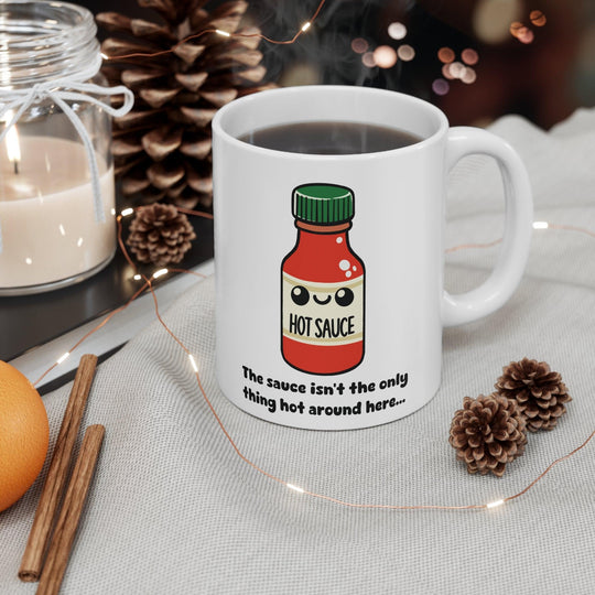 Fun white ceramic mug with a cute hot sauce bottle illustration and the flirty phrase 'You know I can't resist the only thing hot around here,' perfect for adding spice to your morning routine