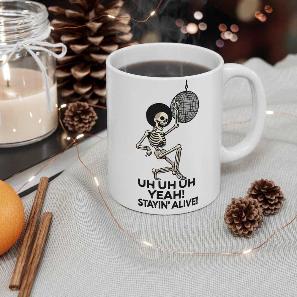 White ceramic mug with a disco-themed illustration and the text 'Stayin' Alive,' a fun, nostalgic nod to classic dance tunes