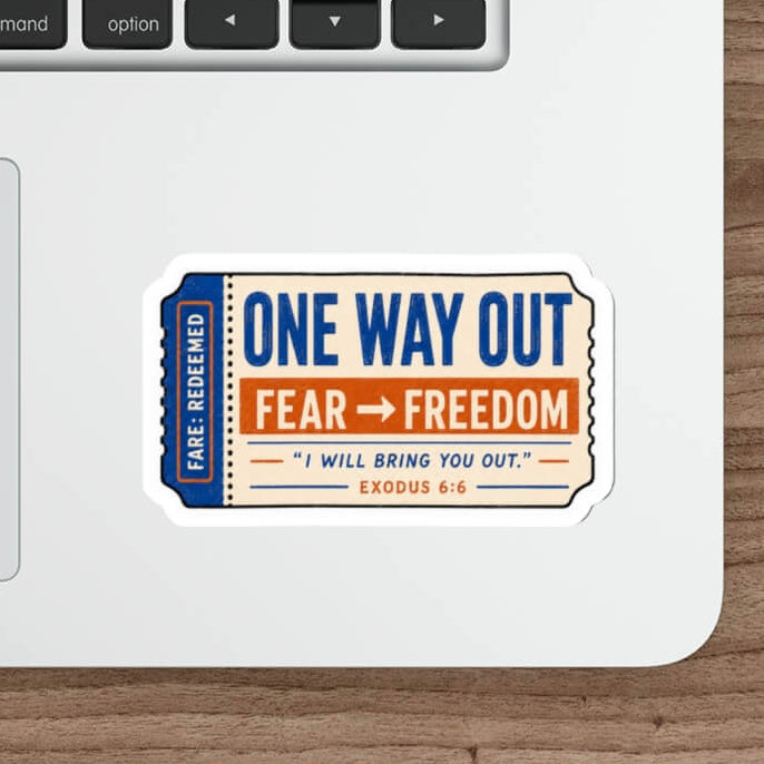 A die-cut sticker with a vintage ticket design reading 'ONE WAY OUT FEAR -> FREEDOM' and 'I WILL BRING YOU OUT' is shown on the palm rest of a white laptop on a wooden desk next to a mouse and stylus.