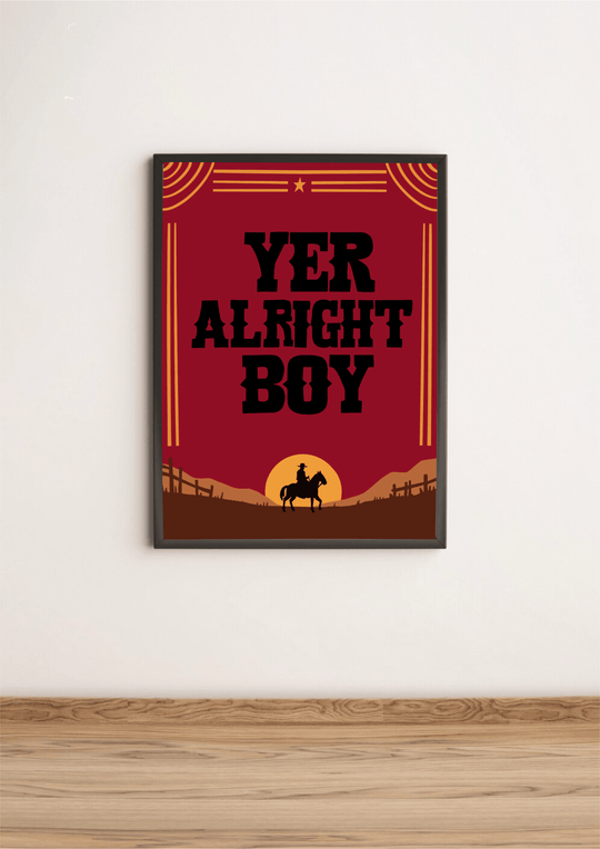 Introducing the "Yer Alright Boy" print—a charming piece that's sure to add a touch of personality to any space! Framed and elegantly displayed on a rustic wooden floor, this artwork showcases bold black letters confidently declaring "YER ALRIGHT BOY." The design features the striking silhouette of a horse and rider, standing proudly against a rich brown landscape dotted with quaint fences. Decorative lines and a star add an extra flair to this captivating scene, all set against a classic white wall. Perfec