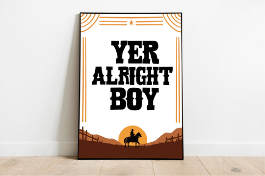 Introducing the "Yer Alright Boy" print—a charming piece that's sure to add a touch of personality to any space! Framed and elegantly displayed on a rustic wooden floor, this artwork showcases bold black letters confidently declaring "YER ALRIGHT BOY." The design features the striking silhouette of a horse and rider, standing proudly against a rich brown landscape dotted with quaint fences. Decorative lines and a star add an extra flair to this captivating scene, all set against a classic white wall. Perfec