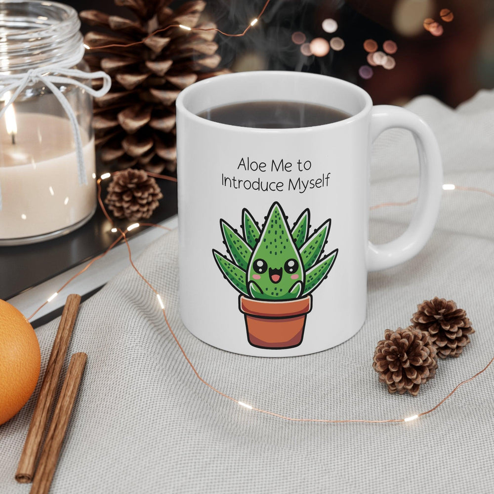 White ceramic mug showcasing a cute aloe plant in a pot with the pun 'Aloe Me to Introduce Myself,' surrounded by a warm, cozy ambiance