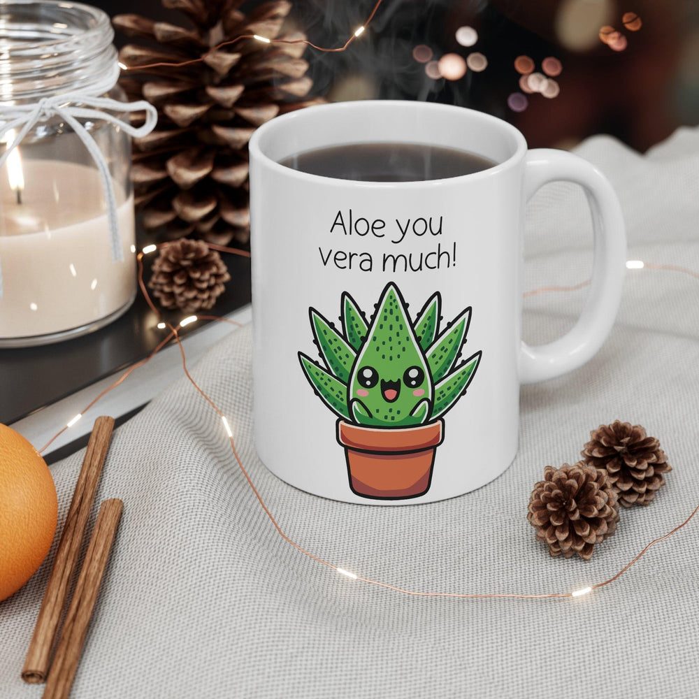un white ceramic mug featuring an adorable aloe plant illustration with the witty phrase 'Aloe You Vera Much,' styled with a wintery, cozy setup