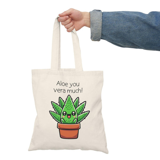 Tote bag featuring a delightful illustration of a cute aloe plant with a smiling face, accompanied by the punny phrase 'Aloe You Very Much.' The design combines playful colors and charming elements, making it a perfect accessory for expressing gratitude and affection in a fun and stylish way."