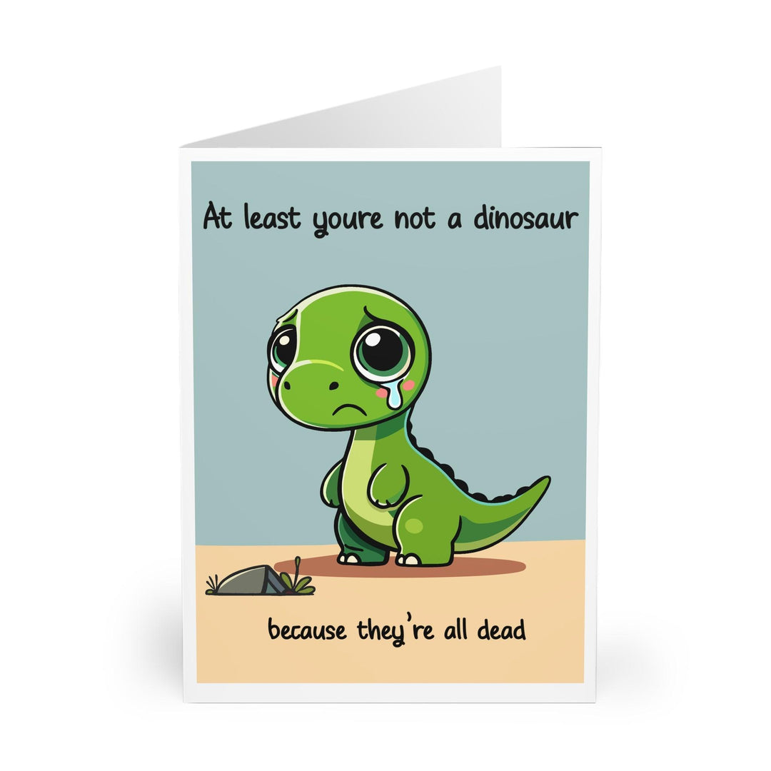 Cheeky greeting card featuring a sad dinosaur with the phrase 'At Least You’re Not a Dinosaur, Because They’re All Dead.' A funny and quirky card perfect for friends with a dark sense of humor - Baby Keo.