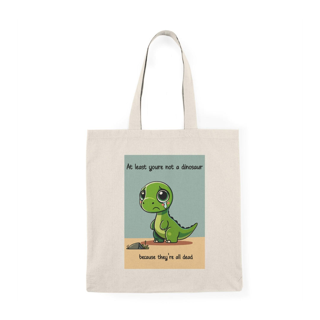 Tote bag featuring a humorous illustration with the phrase 'At Least You're Not a Dinosaur.' The playful design incorporates whimsical graphics and bright colors, adding a lighthearted touch to your everyday carry while making a fun statement.