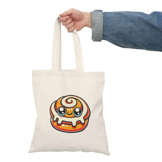 A tote bag featuring a charming kawaii-style cinnamon bun design on a natural canvas background, combining practicality with a playful aesthetic.

