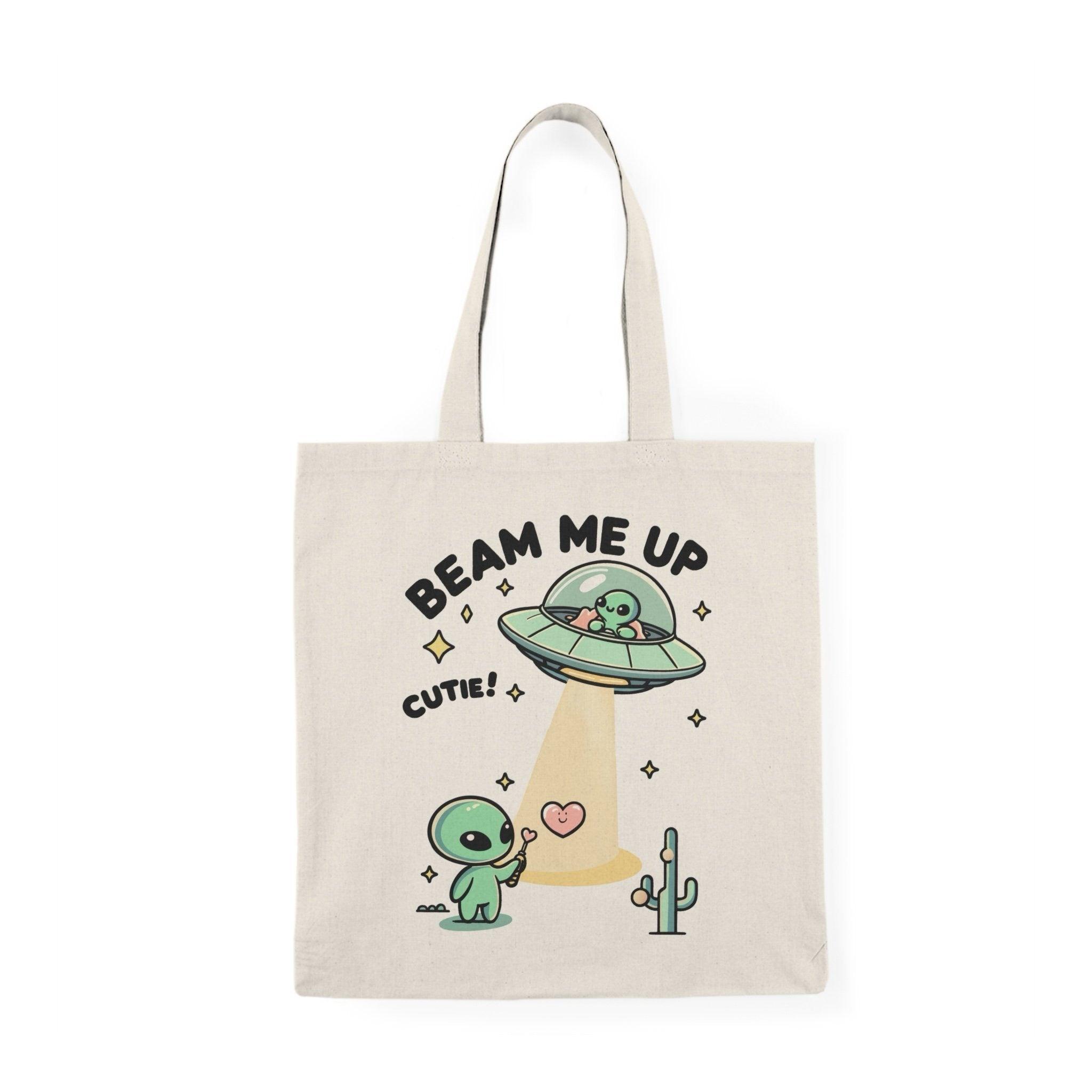 Tote bag featuring a whimsical design with the phrase 'Beam Me Up, Cutie' alongside a charming illustration of a cute alien. The colorful and playful graphics create a fun and quirky vibe, making it an ideal accessory for those who love all things cosmic and adorable."