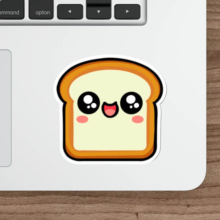 Kawaii-style bread slice sticker with a happy, blushing face placed on a laptop. A fun, cute decal perfect for decorating tech, notebooks, or water bottles