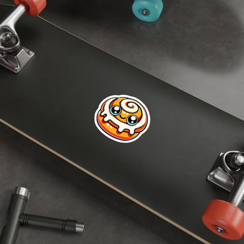A kawaii-style doughnut sticker with vibrant orange glaze and swirling white icing, placed on a laptop next to a keyboard, embodying a cute and playful aesthetic