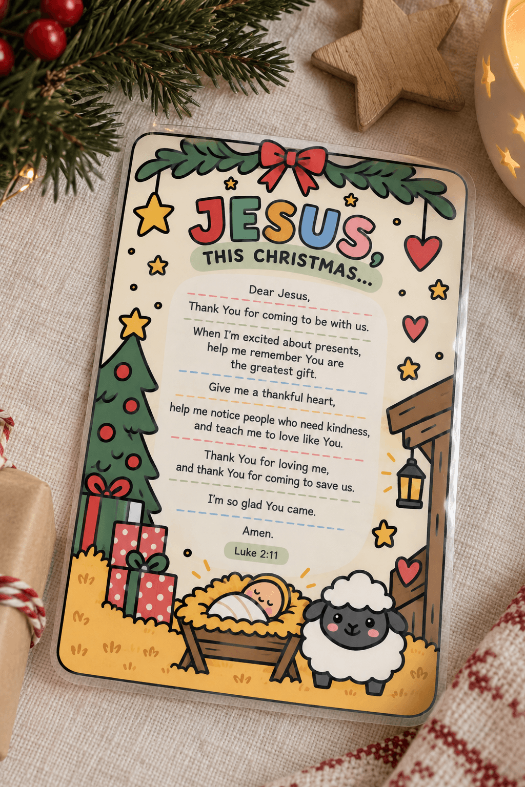 A personalized Christmas greeting card featuring a cartoon sheep, a manger, a tree, and a Bible verse, styled on a textured beige fabric with holiday greenery and a wooden star.