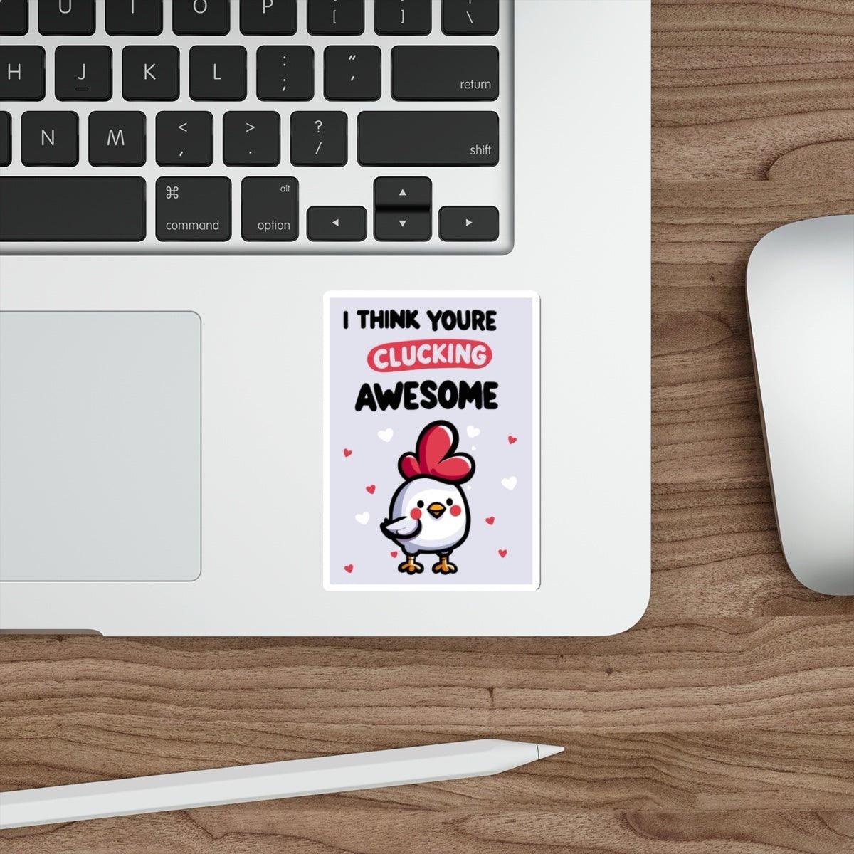A sticker with a graphic of a chicken wearing a heart-shaped hat and text 'I THINK YOU'RE CLUCKING AWESOME' placed on a laptop.