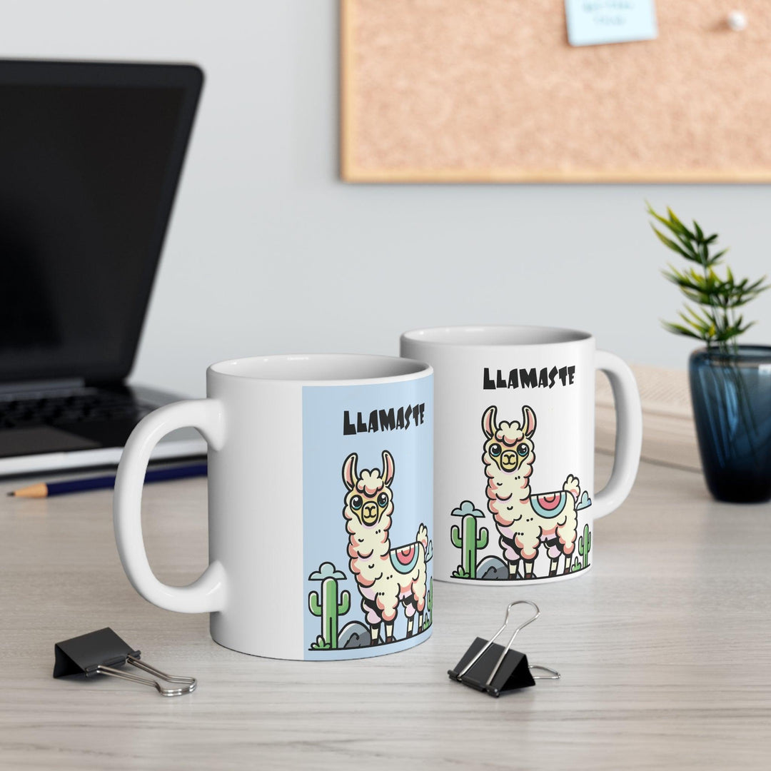 White ceramic mug featuring a charming llama in a yoga pose with the playful text 'Llamaste,' set against a neutral backdrop with cozy pinecones.