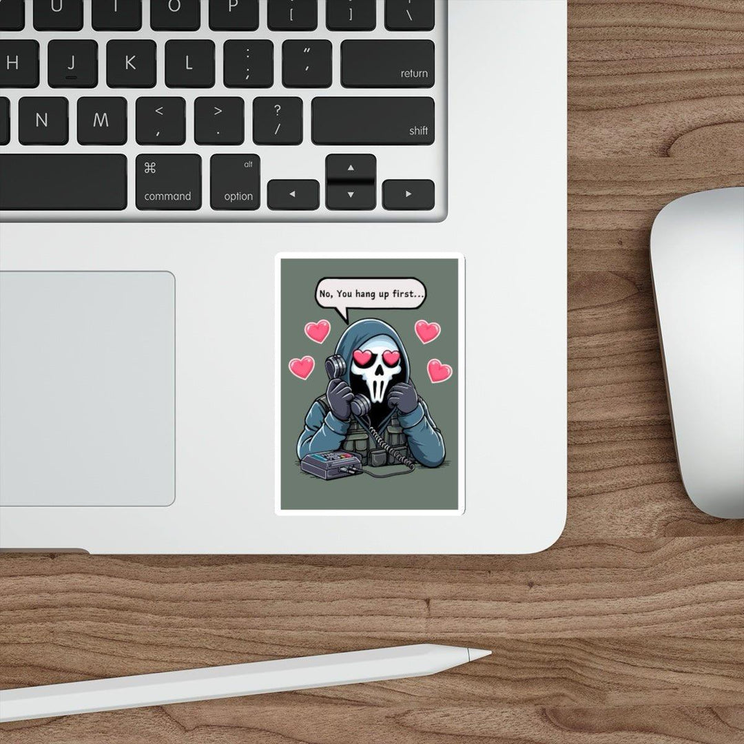 Laptop keyboard and mouse on a wooden desk. A humorous "No, You Hang Up First..." waterproof sticker by Baby Keo is on the laptop, featuring a cartoon character with a skull mask holding a phone, surrounded by hearts. It's perfect for adding personalization to your tech setup.