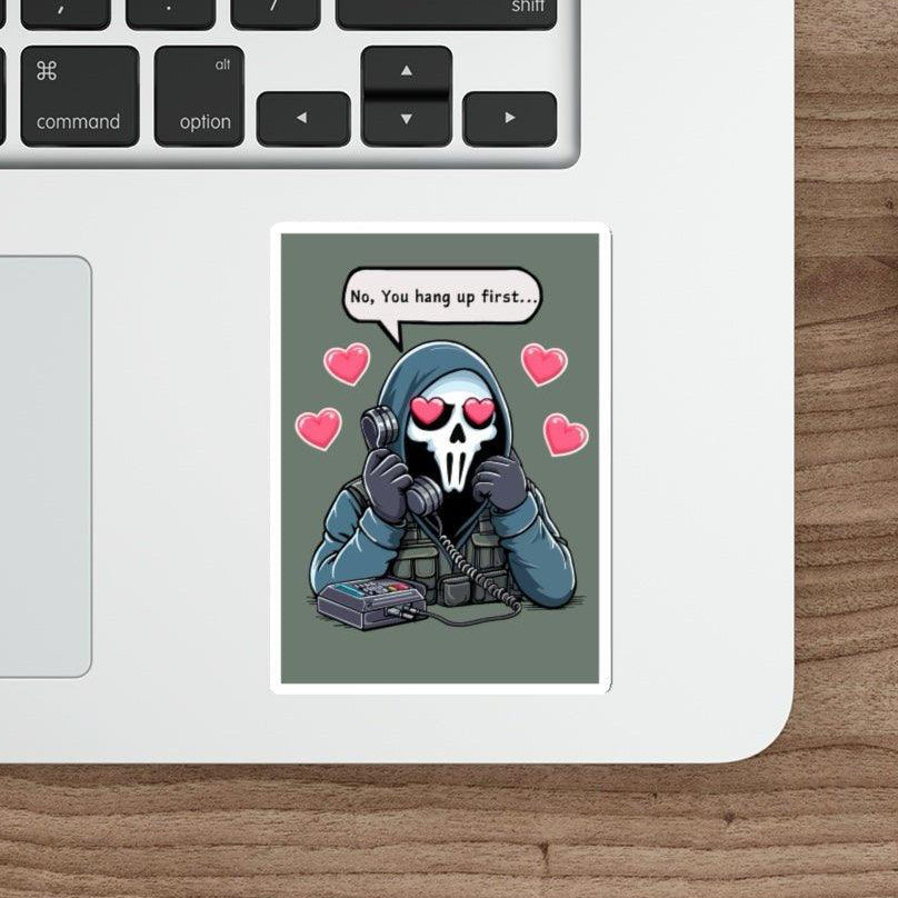 Laptop keyboard and mouse on a wooden desk. A humorous "No, You Hang Up First..." waterproof sticker by Baby Keo is on the laptop, featuring a cartoon character with a skull mask holding a phone, surrounded by hearts. It's perfect for adding personalization to your tech setup.