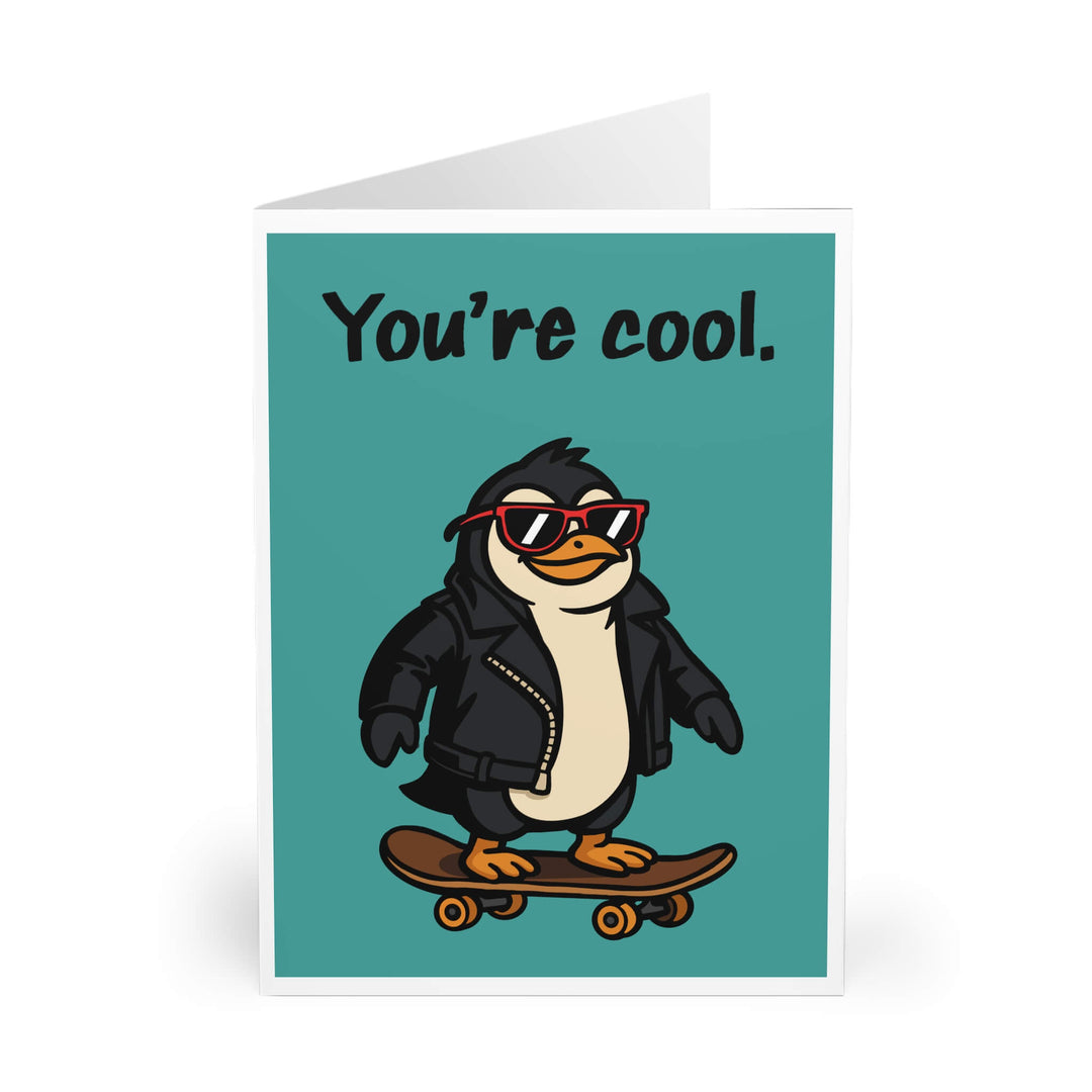 Funny greeting card featuring a cartoon penguin in a leather jacket and red sunglasses riding a skateboard, with the text “You’re cool.”