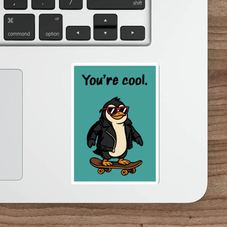 Laptop with a penguin sticker on a wooden desk