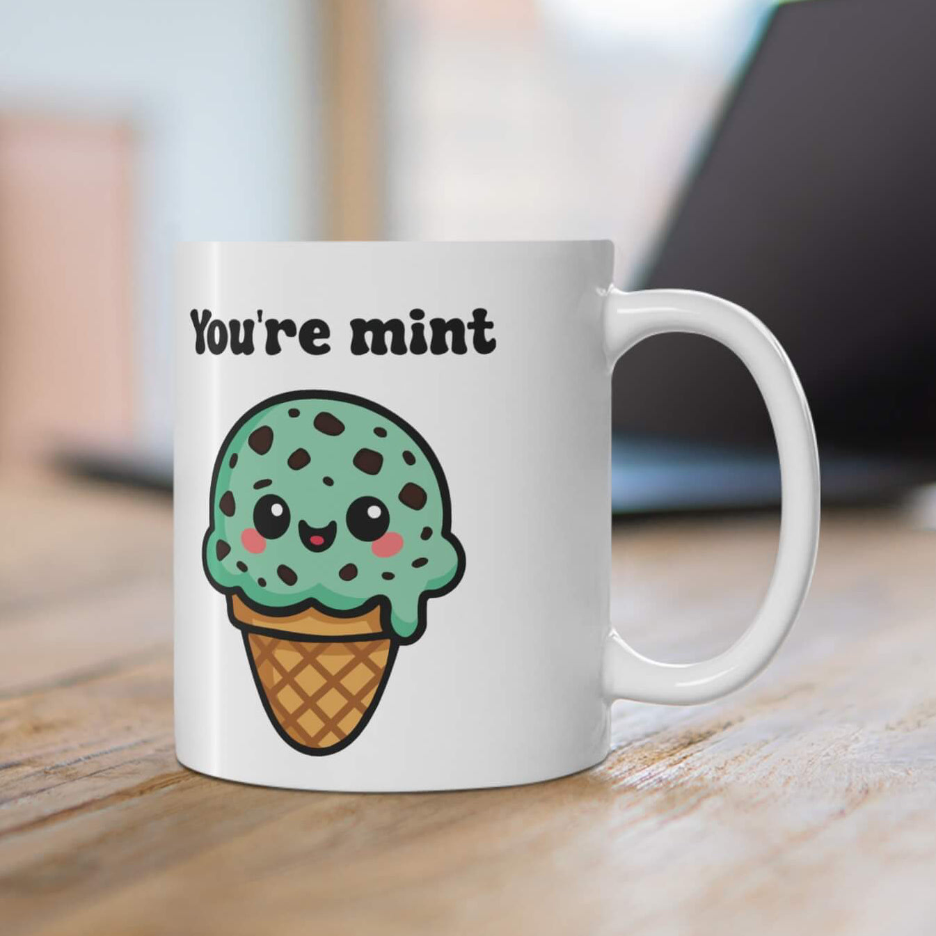 Mint chocolate chip ice cream mug with cute kawaii face and cone, featuring the words "You're Mint" in bold black text on a white ceramic mug.