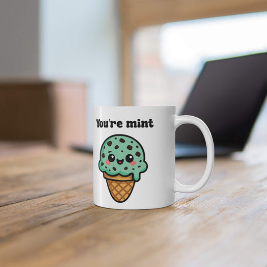 Mint chocolate chip ice cream mug with cute kawaii face and cone, featuring the words "You're Mint" in bold black text on a white ceramic mug.